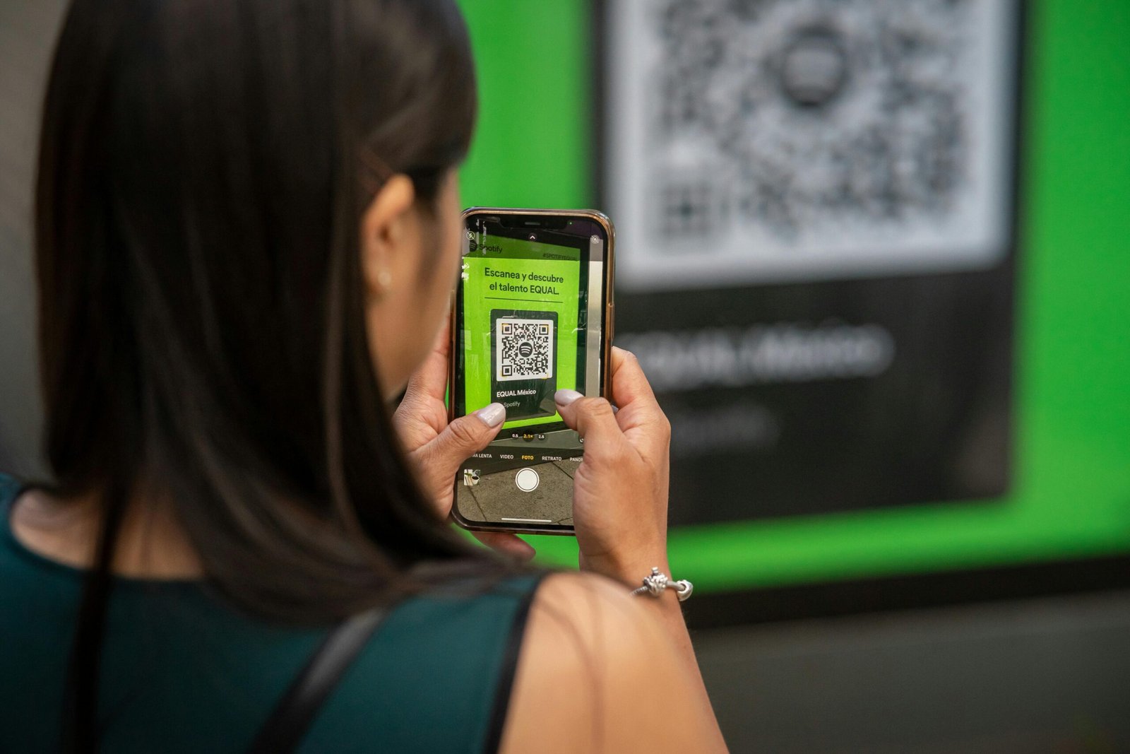 A woman uses her smartphone to scan a QR code in Mexico City, capturing modern technology in action.