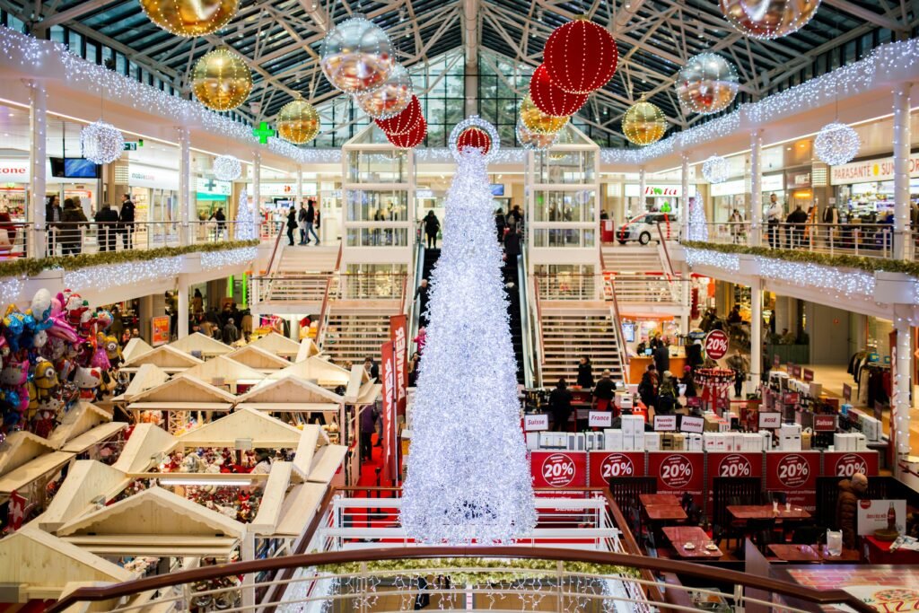 A bustling shopping mall adorned with a large Christmas tree and festive decorations during holiday season.