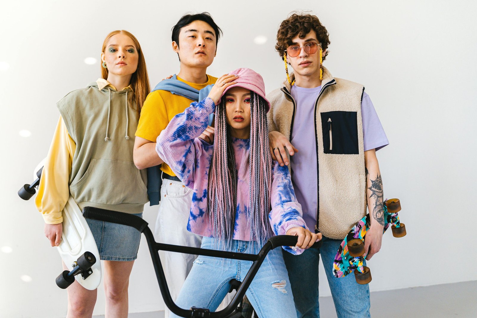 Group of diverse young adults posing fashionably with skateboards in a studio setting.